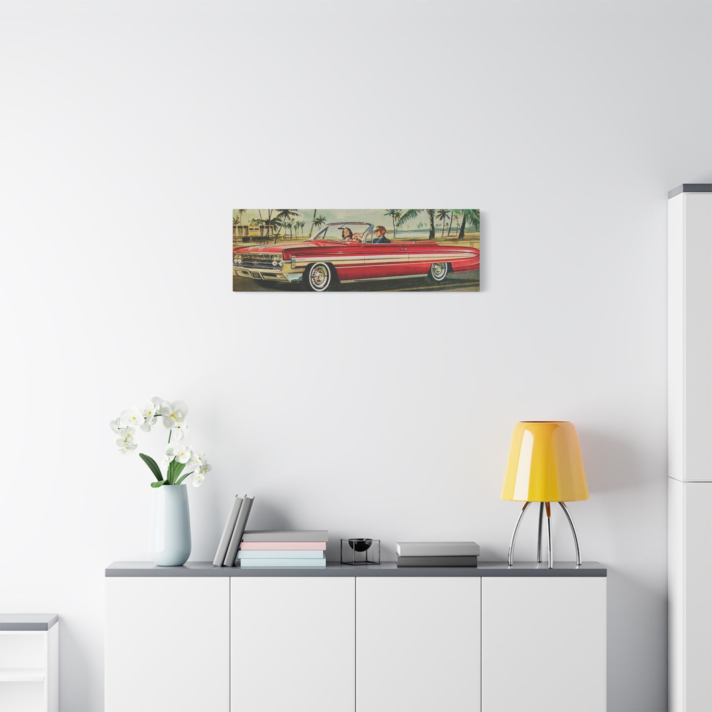  Panoramic view of a red vintage convertible car driving along a coastal road lined with palm trees.